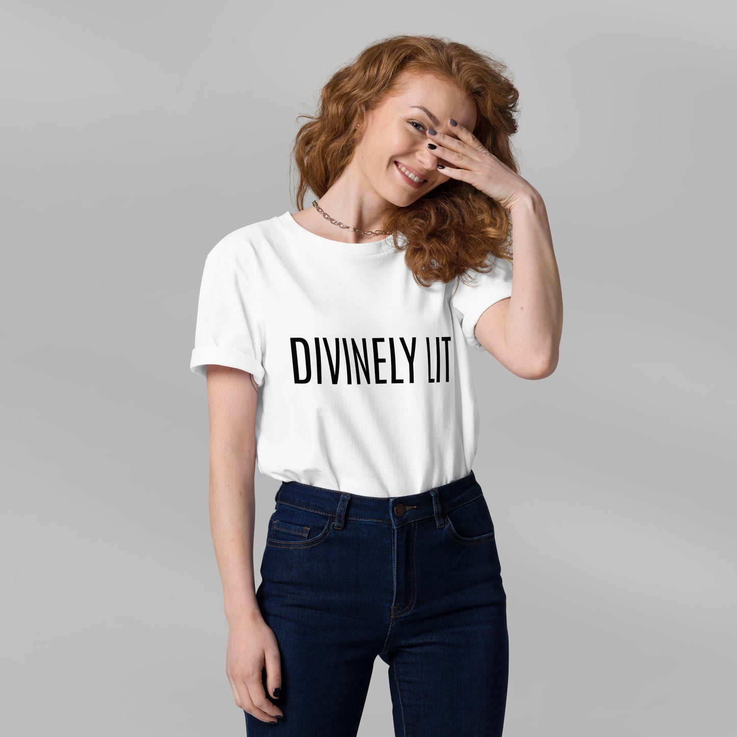 Woman wearing a white t-shirt with 'DIVINELY LIT' text on a plain background