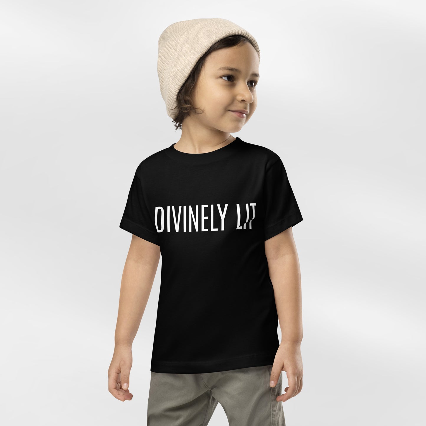Child wearing a black t-shirt with 'DIVINELY LIT' text on a white background