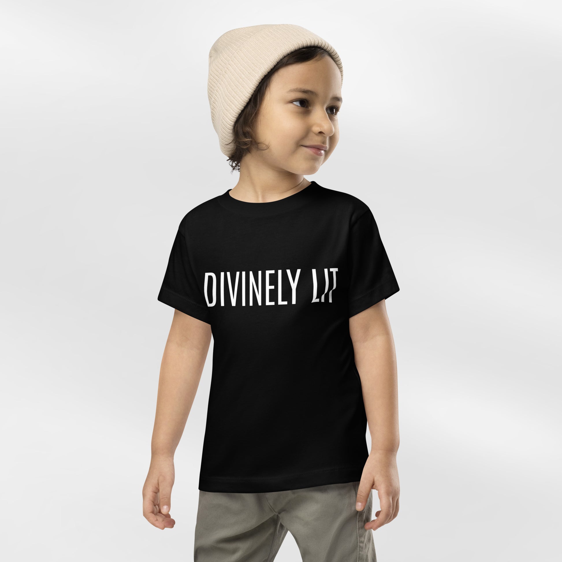Child wearing a black t-shirt with 'DIVINELY LIT' text on a white background